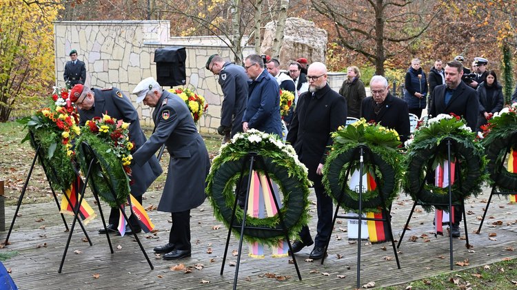 Männer richten an je einem Kranz die Schleifen