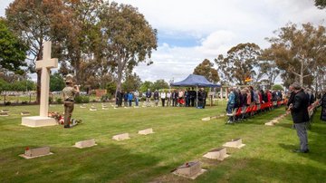 Trompeter spielt vor großer Menschenmenge auf Friedhof