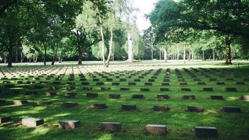 Friedhof mit Grabsteinen, Hochkreuz und Bäumen