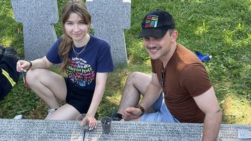 Junge Frau und junger Mann sitzen mit Stiften vor einer Grabplatte