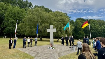 Eine Gruppe steht auf einem Friedhof um ein Hochkreuz.