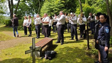 Gruppe Musikerinnen und Musiker auf einer Kriegsgräberstätte