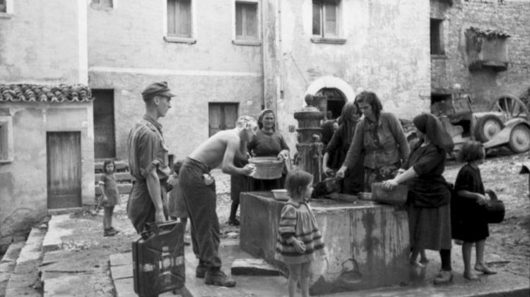 Menschen stehen um einen Brunnen, holen Wasser, waschen sich