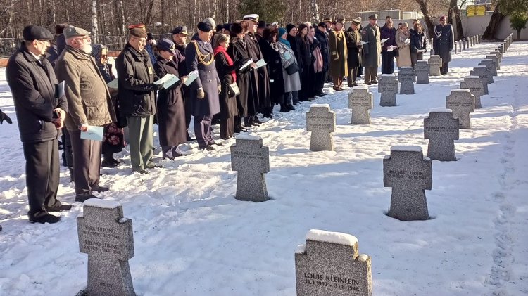 Reihe von Menschen an verschneiten Kriegsgräbern