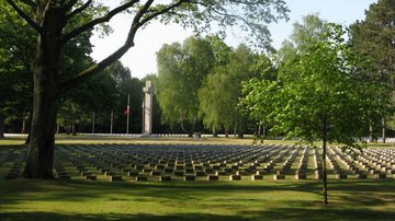 Friedhof mit Grabsteinen, Hochkreuz und Bäumen