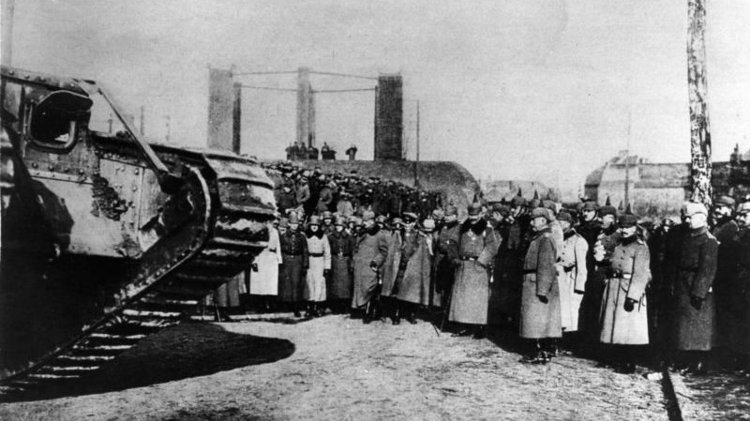 Eine große Gruppe preußischer Soldaten betrachtet einen großen Panzer.