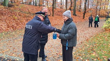 Frau mit Sammeldose und zwei Männer auf Waldweg