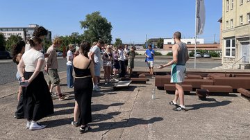 Gruppe junger Leute vor Gedenkstätte erhält Erklärungen