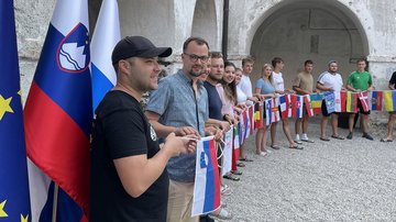 Junge Menschen halten Band mit Flaggen vor historischem Gebäude