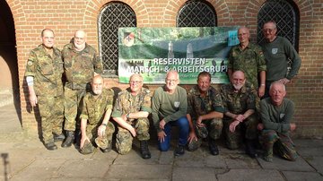 Gruppenfoto mit zehn Männern mit Transparent vor einem Gebäude 