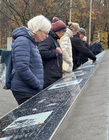 Vier Menschen lesen Infotafeln auf steinernem Pult