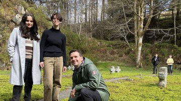 Vier Schüler und ein Lehrer befinden sich auf einem Friedhof zwischen Grabkreuzen.