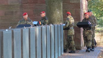 Soldaten mit Särgen gehen um Stelen herum
