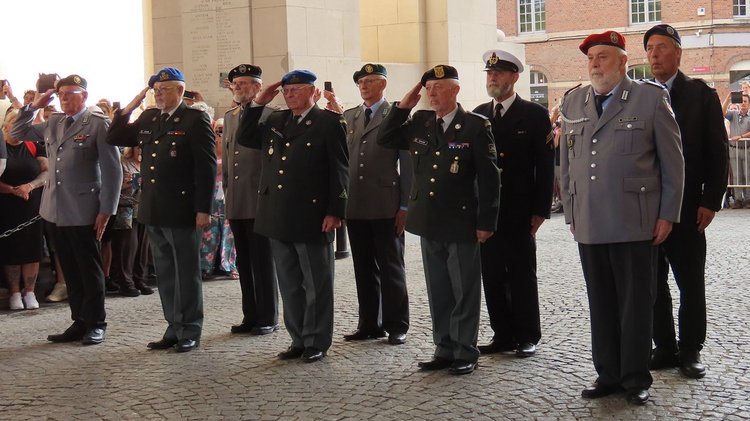 Neun Männer in Uniform, vier grüßen militärisch