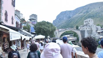 A group of young people with the Old Bridge of Mostar in the background.