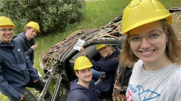 Vier junge Menschen sind an einem Autowrack