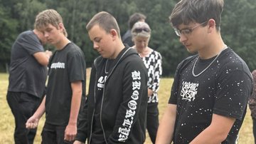 Drei Jungen stehen in einer Reihe und halten ihren Kopf gesenkt.