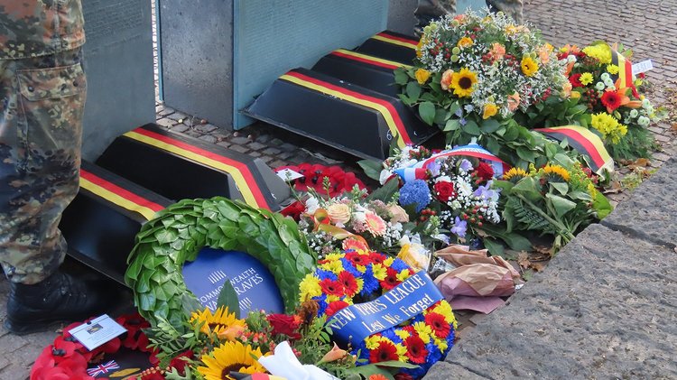 Fünf schwarze Särge mit Kränzen und Gestecken