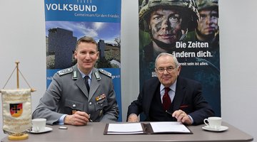 Mann in Uniform und Mann in Zivil unterzeichnen einen Vertrag.