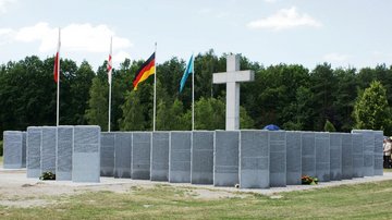Granitstelen mit Namen vor Hochkreuz und drei Flaggen