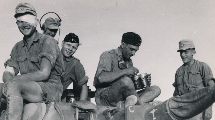 Fünf Soldaten sitzen zusammen, essen und lachen.