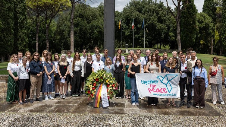 Gruppe mit Kranz und Transparent vor dem Hochkreuz auf dem Friedhof