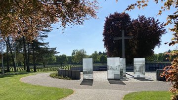 Blick auf das Hochkreuz mit Gedenkzeichen. Im Hintergrund sieht man die Gräberreihen.