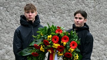 Zwei Jugendliche tragen Gedenkkranz