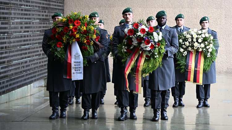 Männer in Uniform tragen Kränze