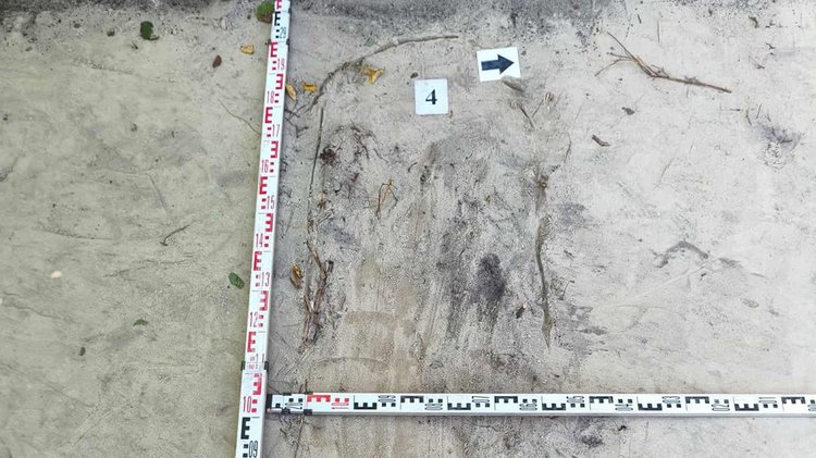 Zwei Messlatten in rechtem Winkel auf Sandboden ausgelegt