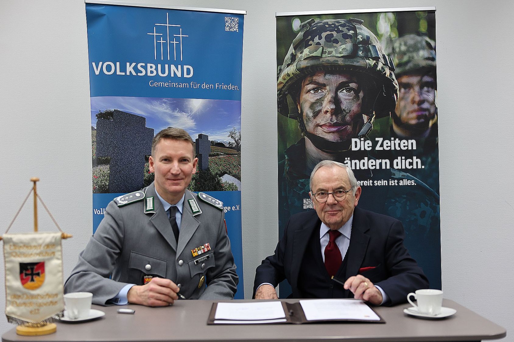 Mann in Uniform und Mann in Zivil unterzeichnen einen Vertrag.
